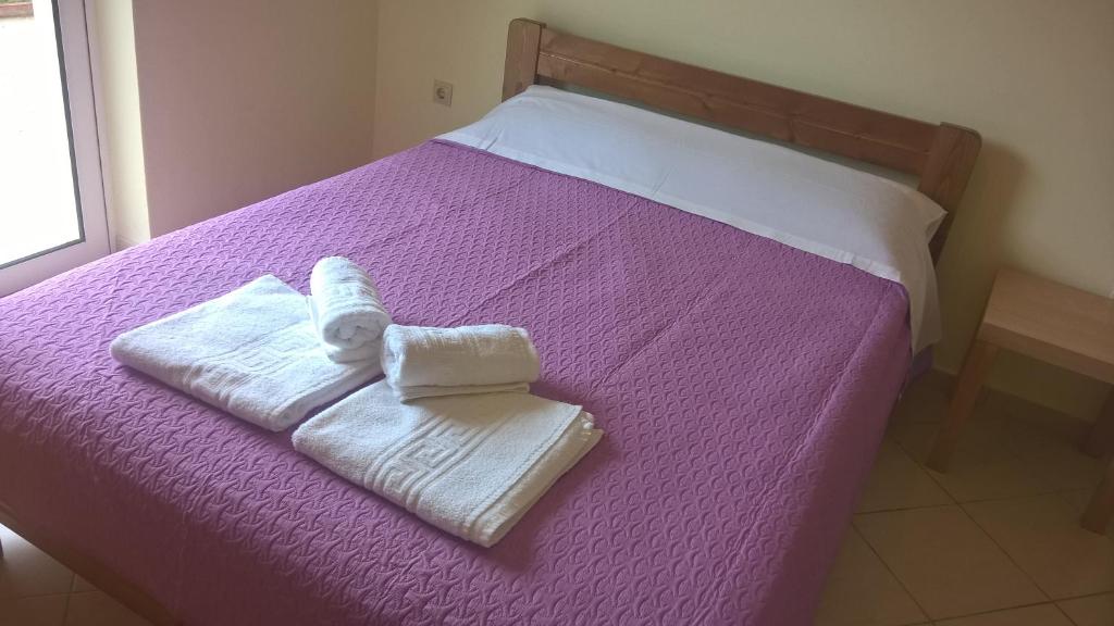 美西尼HOLIDAYS APARTMENT ΜΕΣΣΗΝΗ的紫色的床,上面有两条毛巾