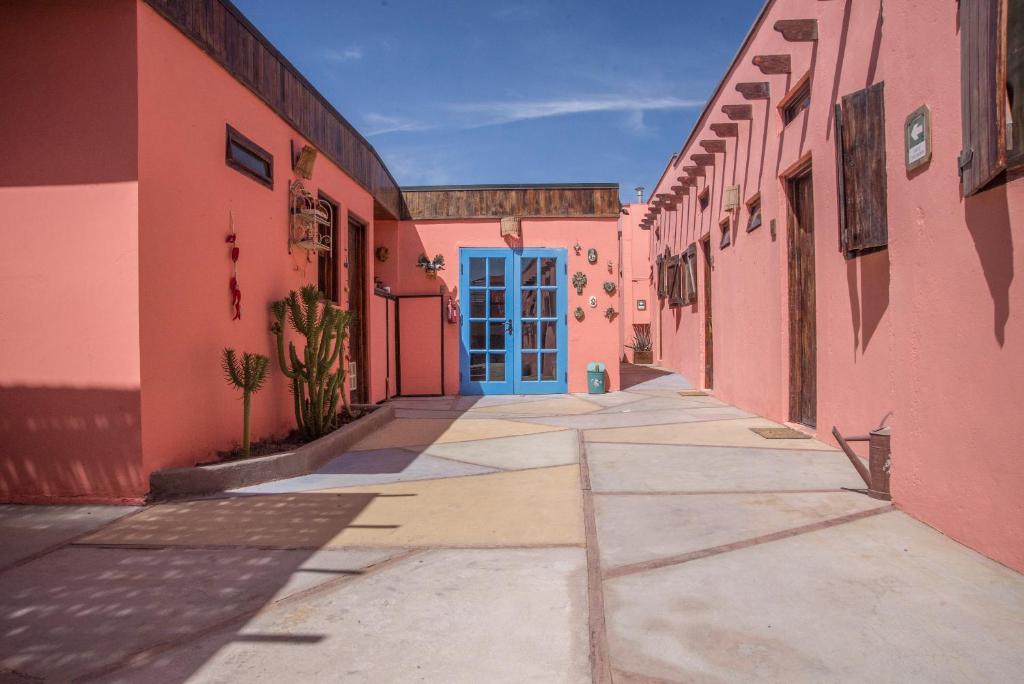 圣佩德罗·德·阿塔卡马蒙特帕尔多旅舍的粉红色建筑中一条带蓝色门的小巷