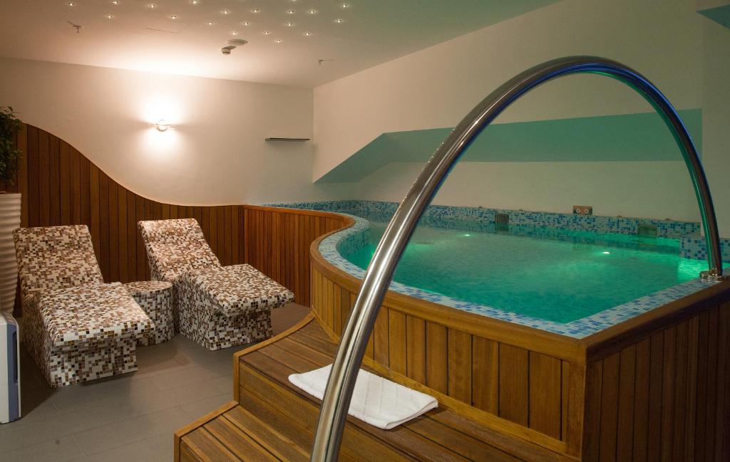 波德戈里察奥利尔酒店的酒店客房带按摩浴缸,带椅子。