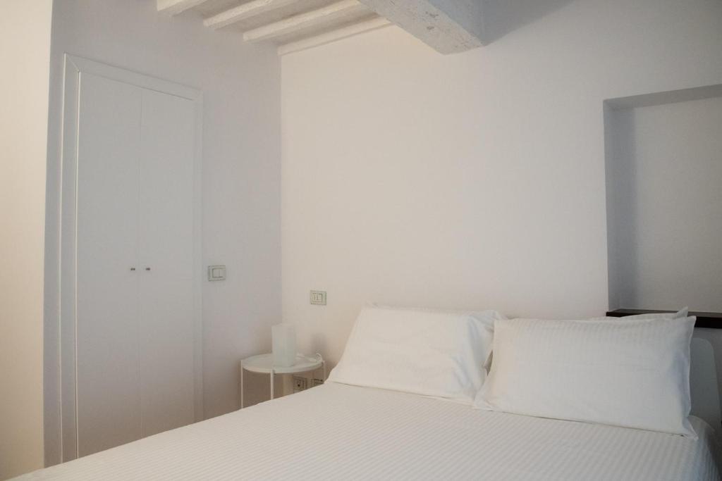 锡耶纳La casa in Camollia的白色卧室配有带白色枕头的床