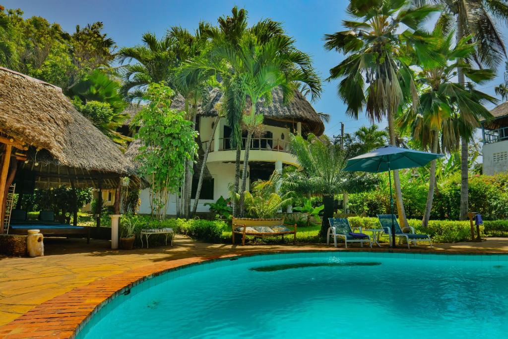 迪亚尼海滩Upani in Diani的棕榈树屋前的游泳池