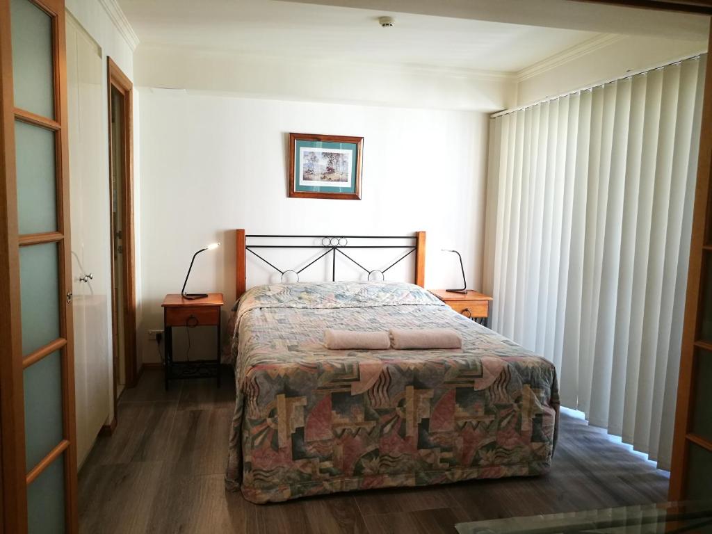 布里斯班莱卡特赛格布鲁克酒店的一间卧室配有一张床、两张桌子和两盏灯。