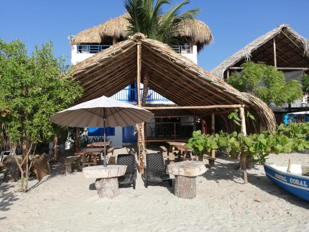RincónHostal Coral Blue的海滩上的一把草伞和桌椅