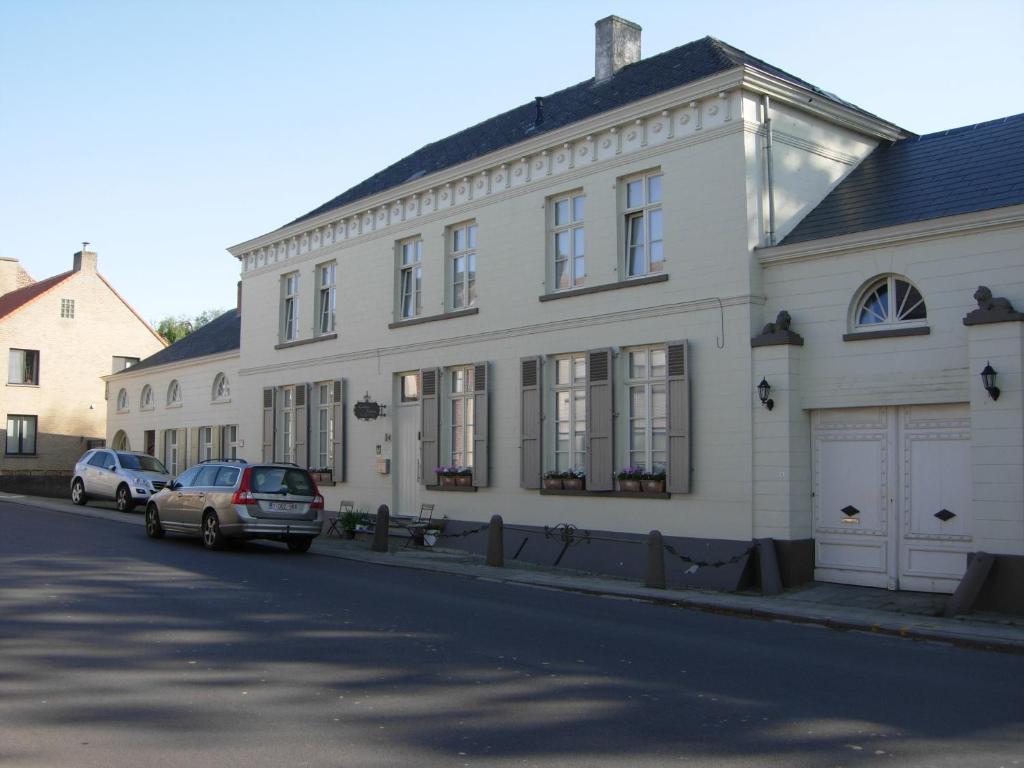 雷尼格尔斯特维达斯图斯旅馆的一座白色的建筑,前面有汽车停放