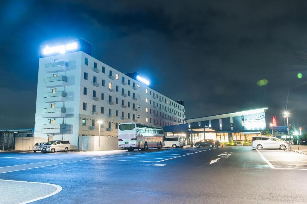 仙台仙台海滨通多米快捷酒店 的一座有汽车在晚上停在停车场的建筑