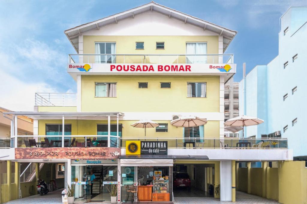 邦比尼亚斯Pousada Bomar Bombinhas的黄色的建筑,上面有读书普斯卡文的标志