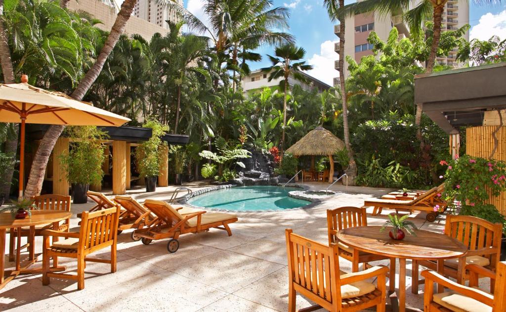 檀香山CASTLE Bamboo Waikīkī Hotel的一个带桌椅的庭院和一个游泳池