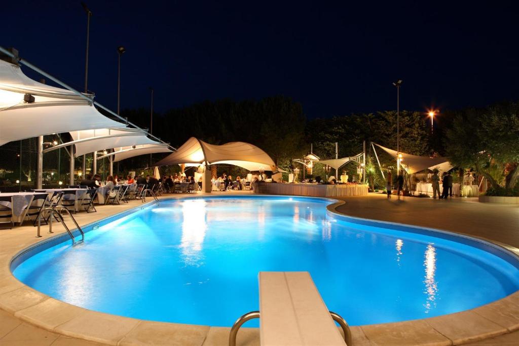 维多利亚兰墅酒店的夜间游泳池,配有桌子和遮阳伞