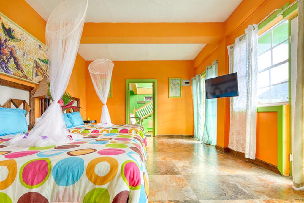苏弗里耶尔Villa Des Pitons的一间卧室设有橙色的墙壁和一张带彩色床罩的床。