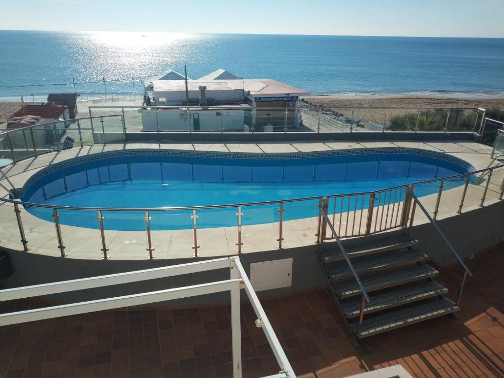 克莉丝蒂娜岛Islantilla-Apartamento con piscina y garaje en primera línea de playa的一座游泳池,位于一座毗邻大海的建筑的顶部