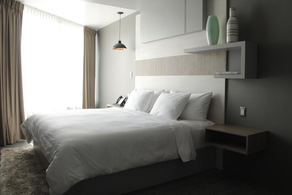 帕丘卡德索托ESDUMA HK HOTEL Pachuca的卧室配有一张大白色床和窗户