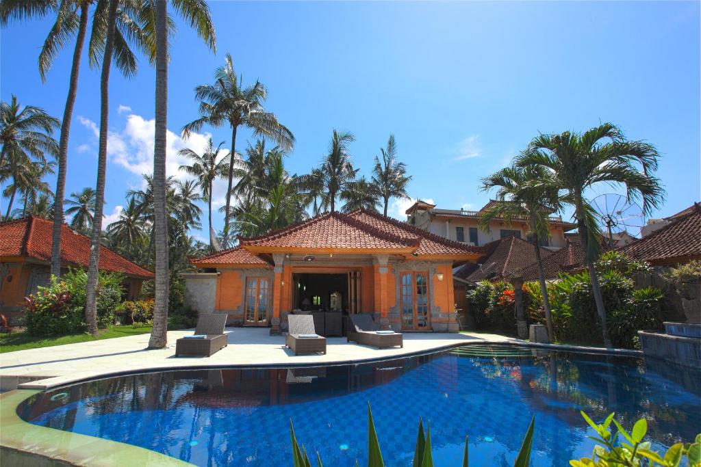 甘地达萨拉玛别墅酒店的棕榈树屋前的游泳池