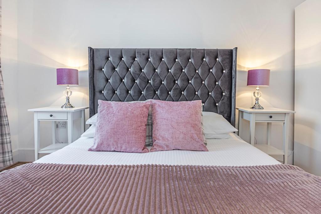 伦敦Knightsbridge Dream Apartment的一间卧室配有带粉红色枕头的床和两张桌子