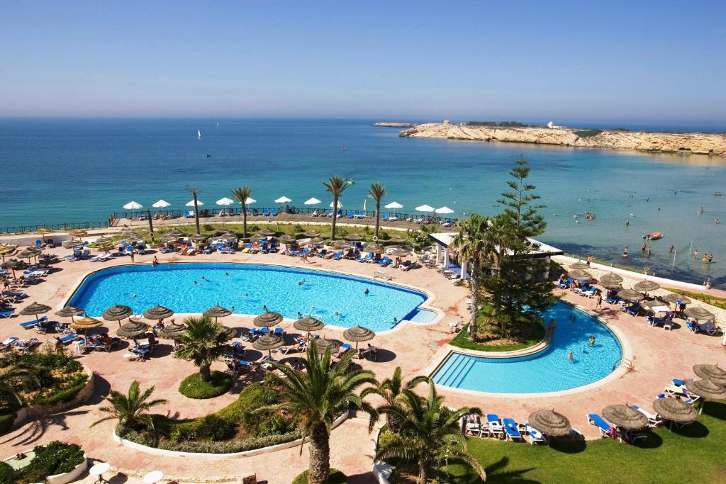 莫纳斯提尔Regency Hotel & Spa的享有带遮阳伞的游泳池和大海的顶部景致