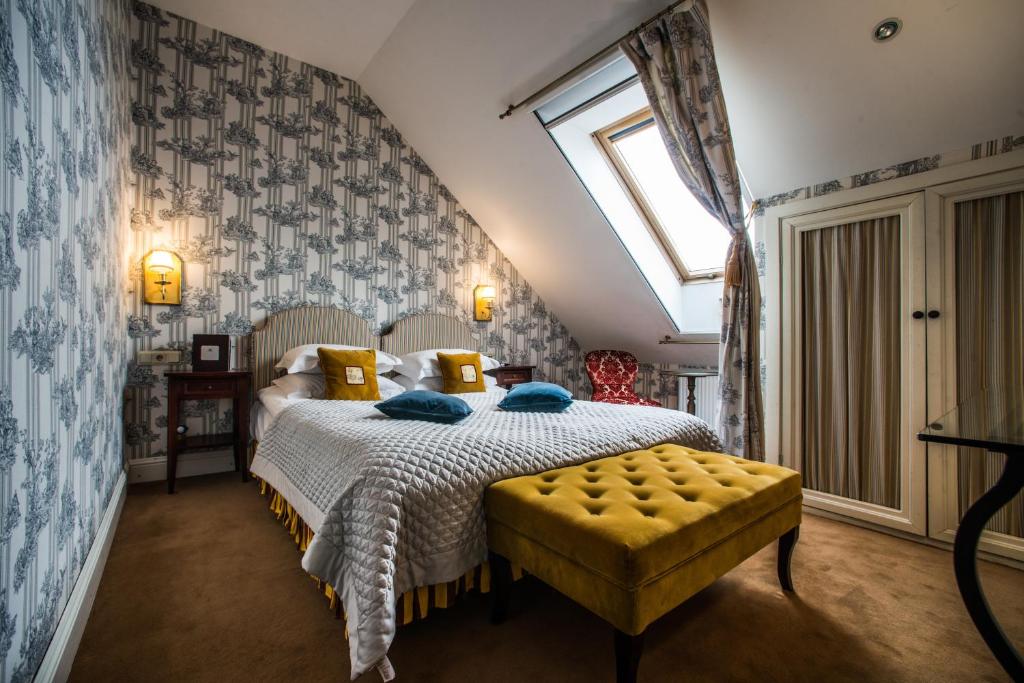 特拉凯圆桌俱乐部酒店的一间卧室配有一张带黄色搁脚凳和窗户的床