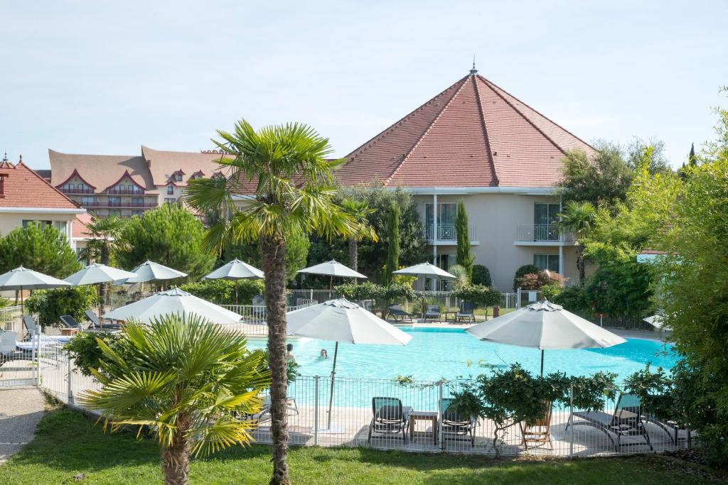 圣艾尼昂Les Jardins de Beauval的享有带遮阳伞的度假村游泳池的景色