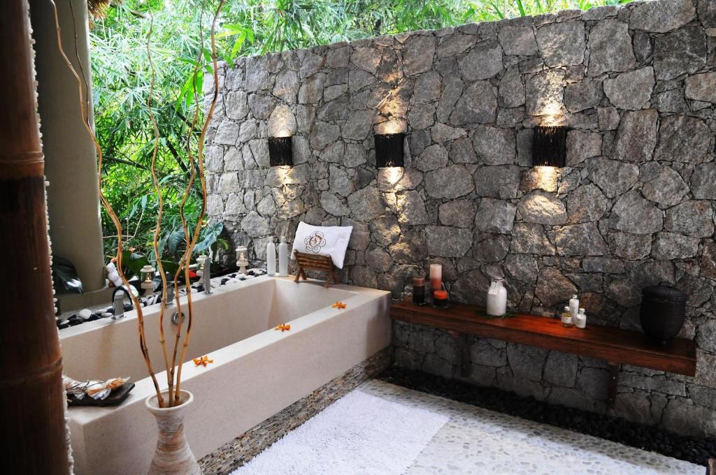 拉迪格岛乐德麦尼得劳昂吉瑞尔度假村和Spa的带浴缸和石墙的浴室。