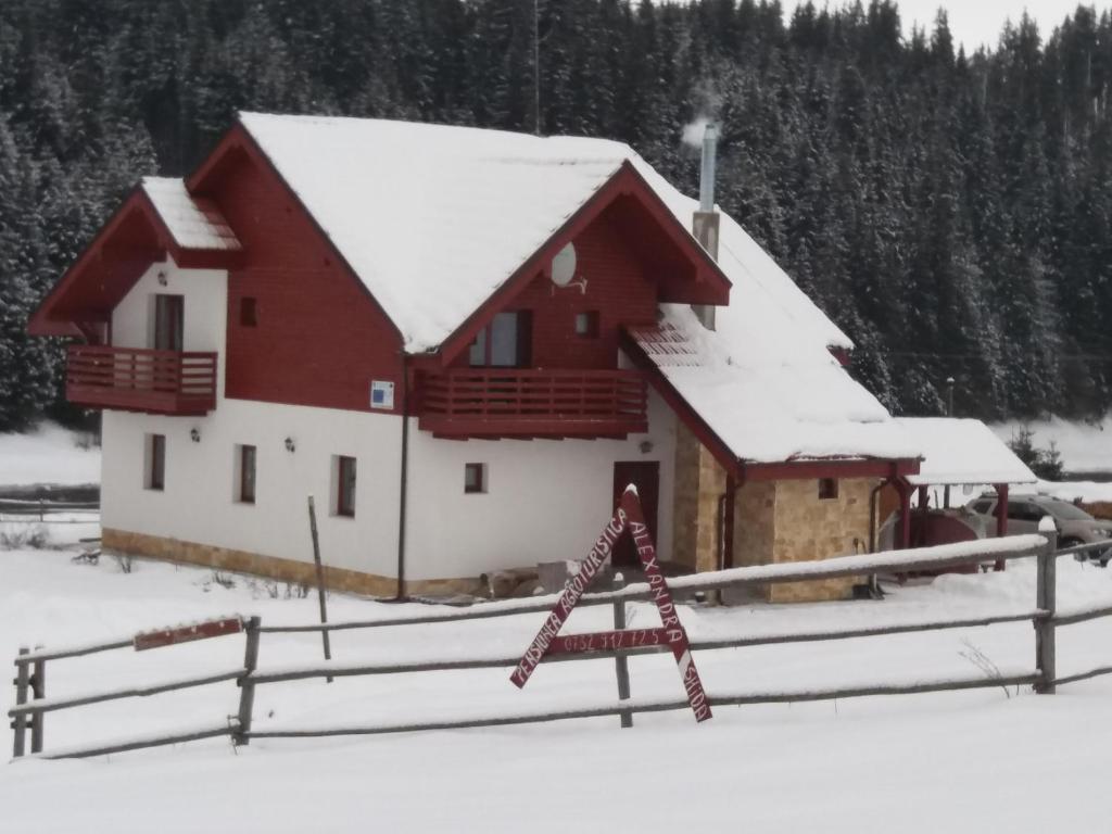 SmidaPensiunea Agroturistica Alexandra的雪盖屋顶的红白色谷仓