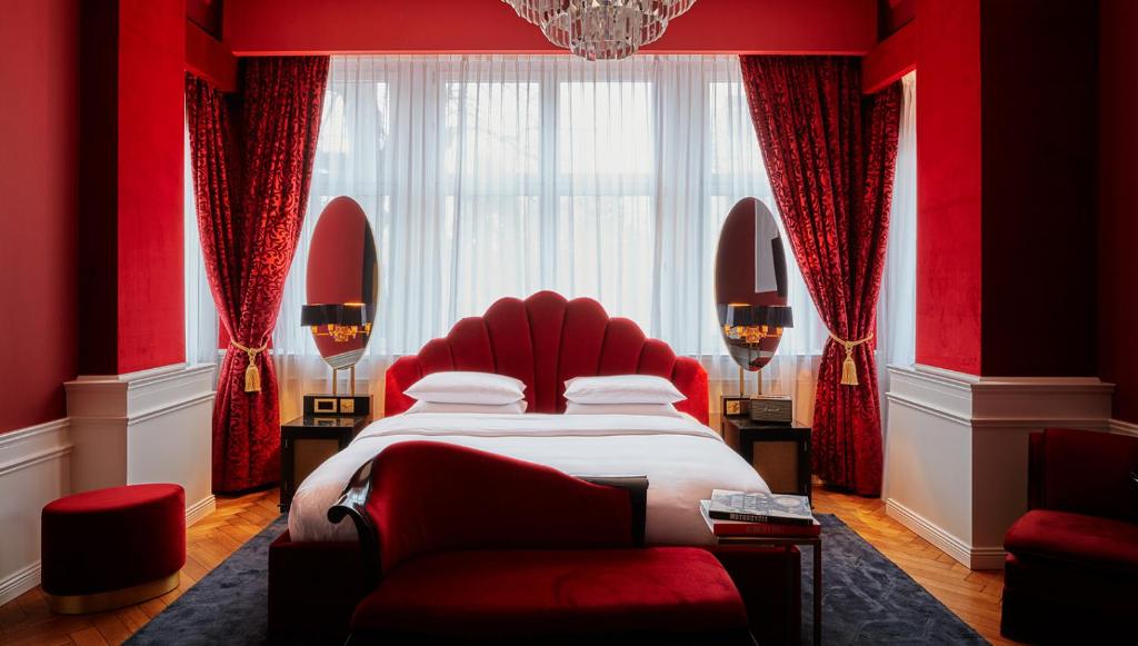柏林Provocateur Berlin, a Member of Design Hotels的红色卧室配有床和红色椅子