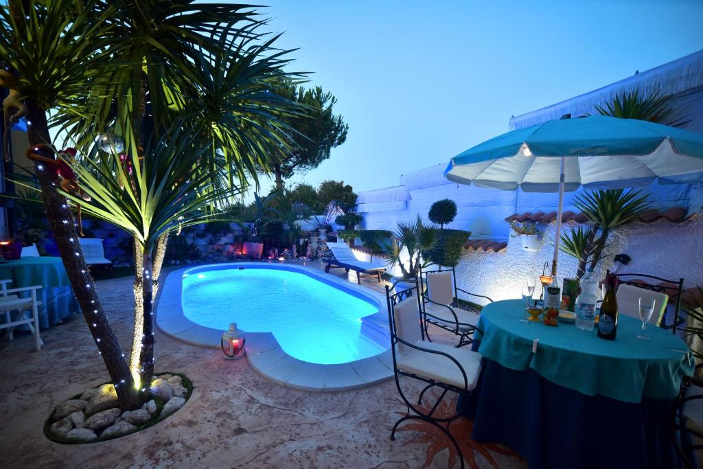 圣焦万尼泰亚蒂诺B&B Oasi Degli Angeli的一个带桌子和棕榈树的游泳池