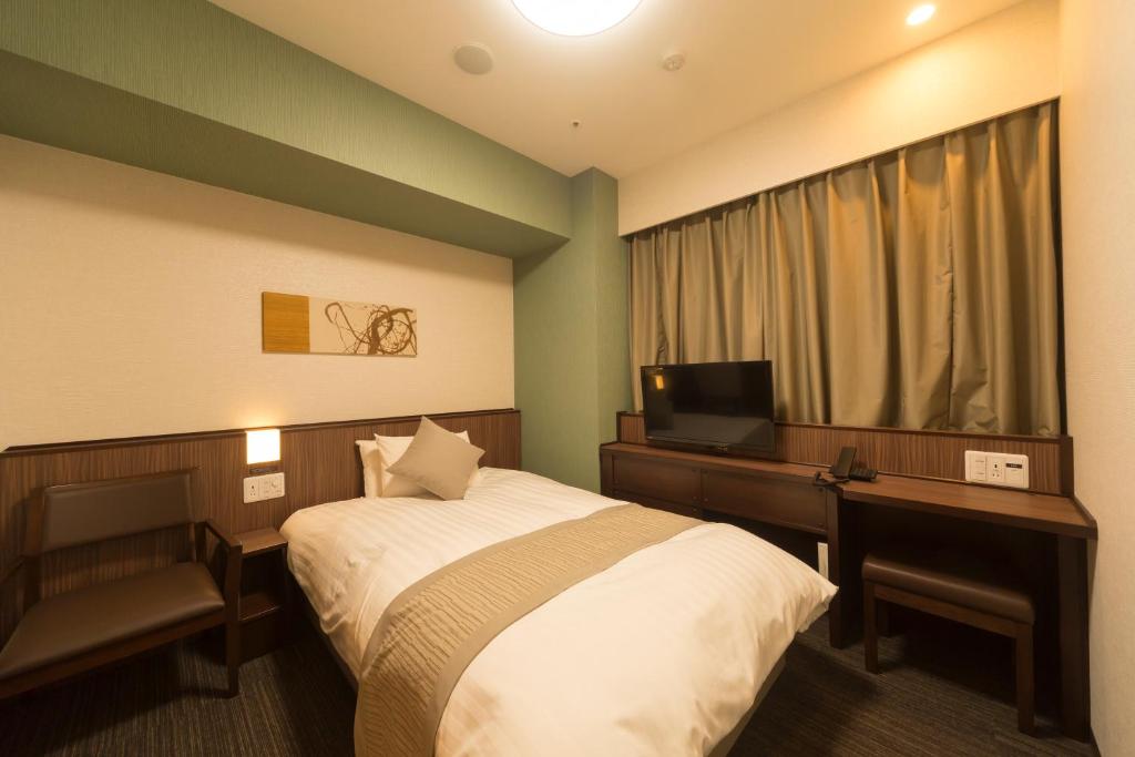 东京明神之汤神田尊贵多尔米酒店的酒店客房配有一张床、一张书桌和一台电视。