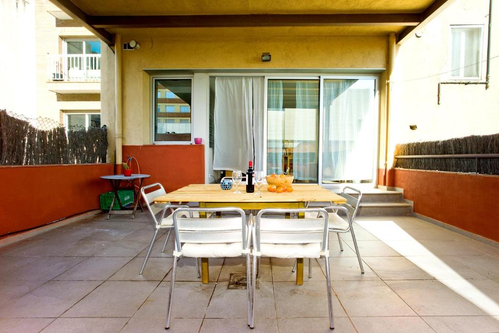 巴塞罗那Amplio apartamento con terraza en zona muy tranquila的天井上的木桌和椅子
