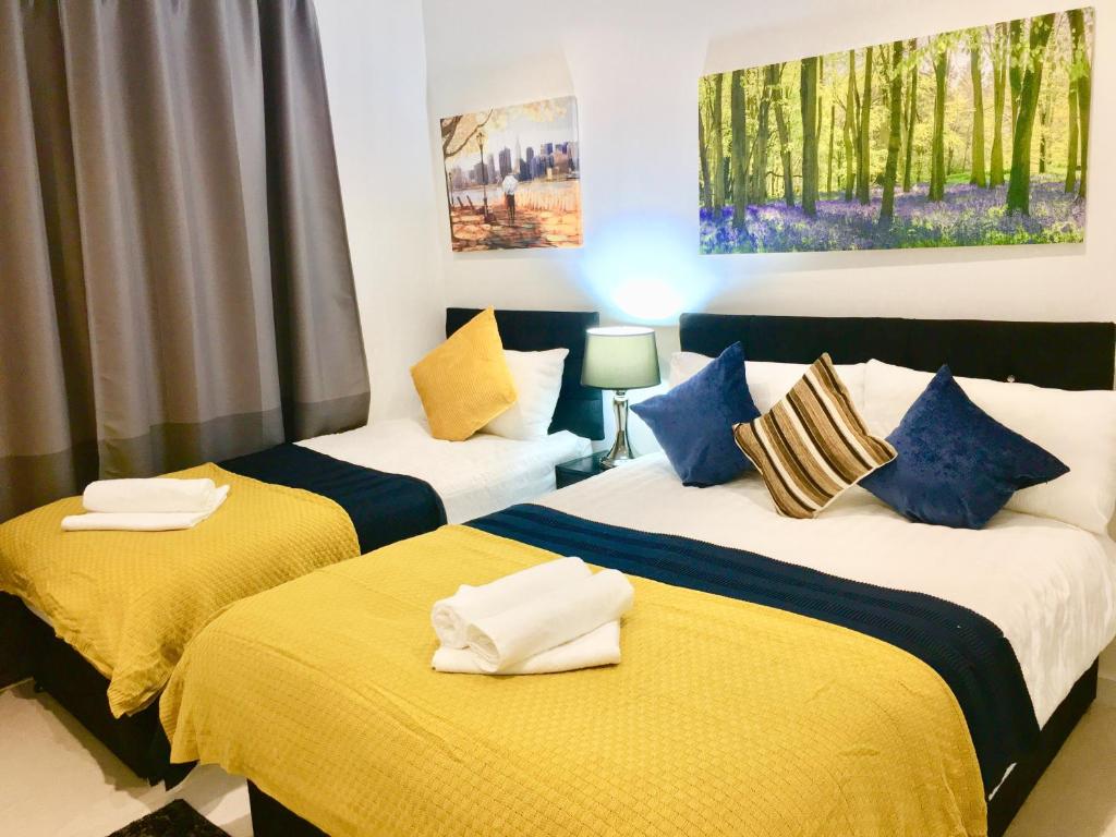 伦敦Dockland Excel 2 Bedroom Apartment的一间卧室配有两张黄色和蓝色床单的床