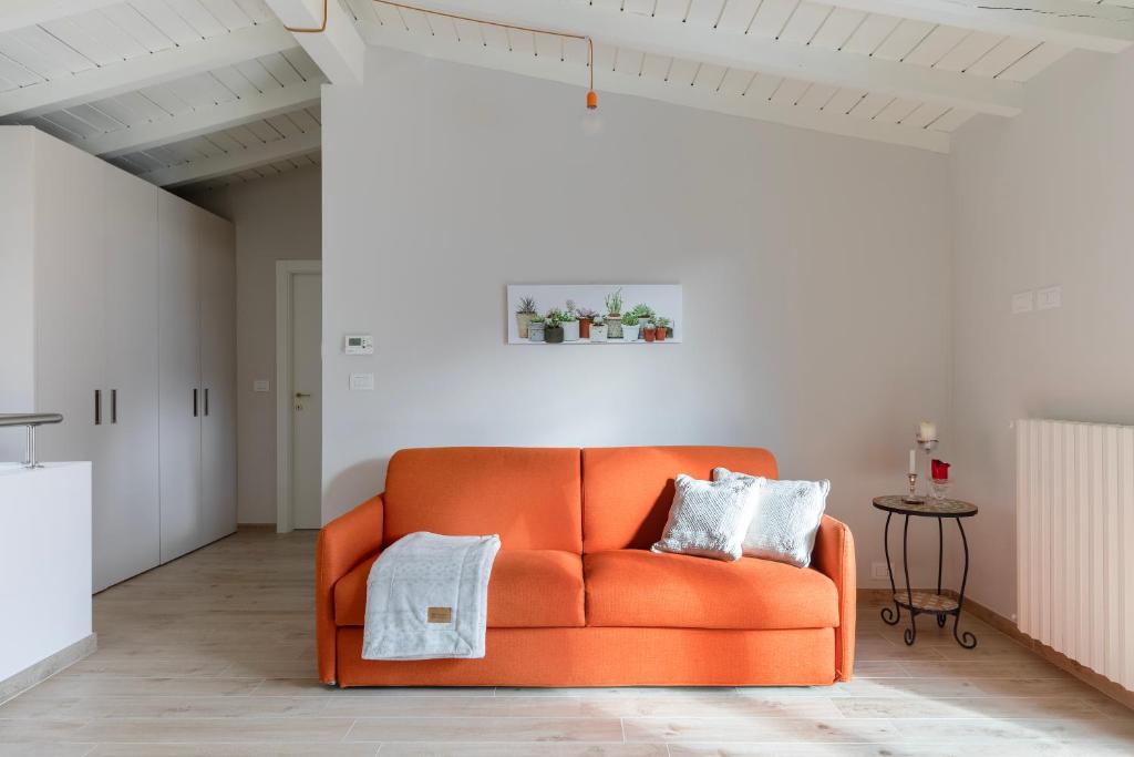伦诺Mansarda I Cipressi的白色的房间里摆放着橙色的沙发,配有桌子