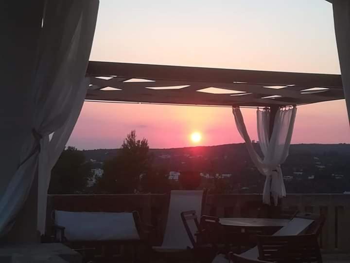 莱乌卡Villa Pedaci B&B的阳台享有日落美景,配有桌椅。