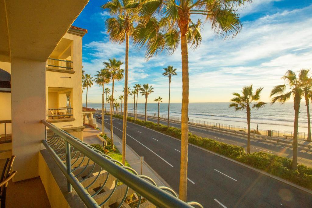 卡尔斯巴德塔马拉克海滩酒店的阳台种有棕榈树,拥有一条道路和大海