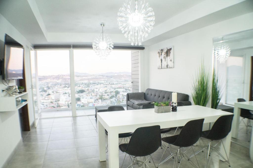 提华纳Luxurious Condo & unparalleled Comfort inTijuana的一间配备有白色桌椅的用餐室