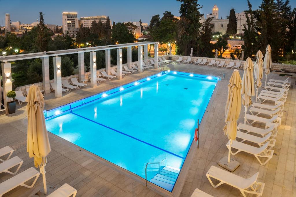 耶路撒冷耶路撒冷莱昂纳多广场酒店的一个带椅子和遮阳伞的大型游泳池