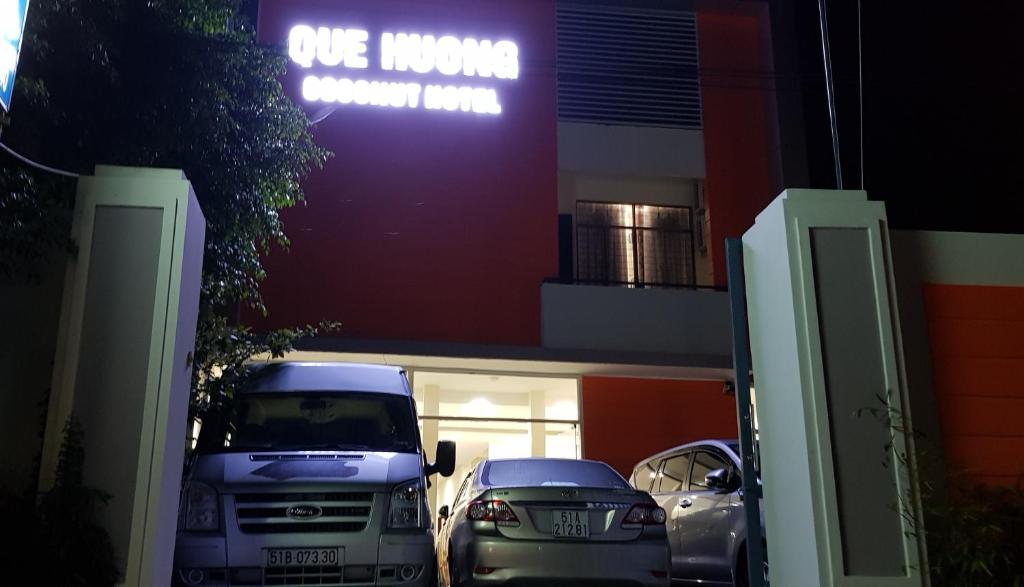 Giồng Tú ÐiềnQue Huong Coconut Hotel的停在大楼前的一组汽车