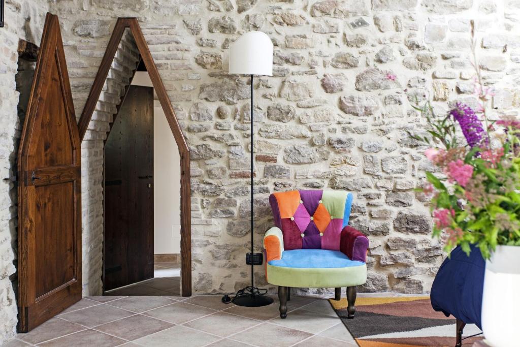 阿西西Agriturismo La Palazzetta di Assisi的石墙房间里一张五彩缤纷的椅子