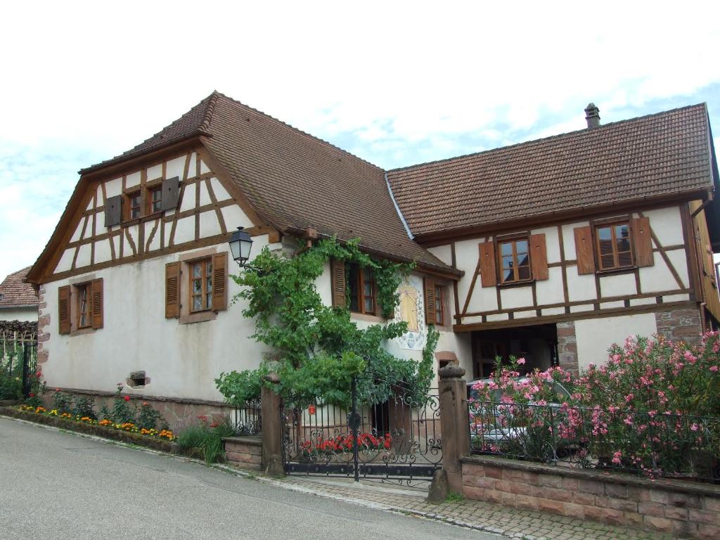 Triembach-au-ValGîte "AU CADRAN SOLAIRE"的白色和棕色的房子,有栅栏和鲜花