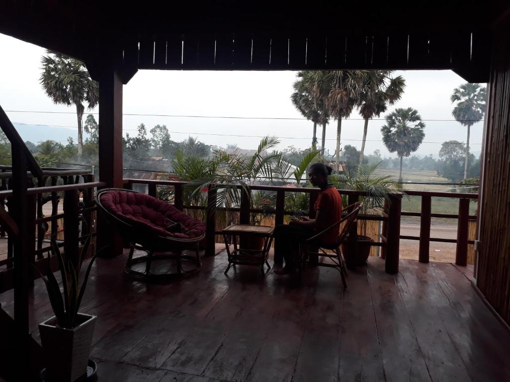 贡布Sunshine Hotel Kampot的坐在门廊桌子上的人