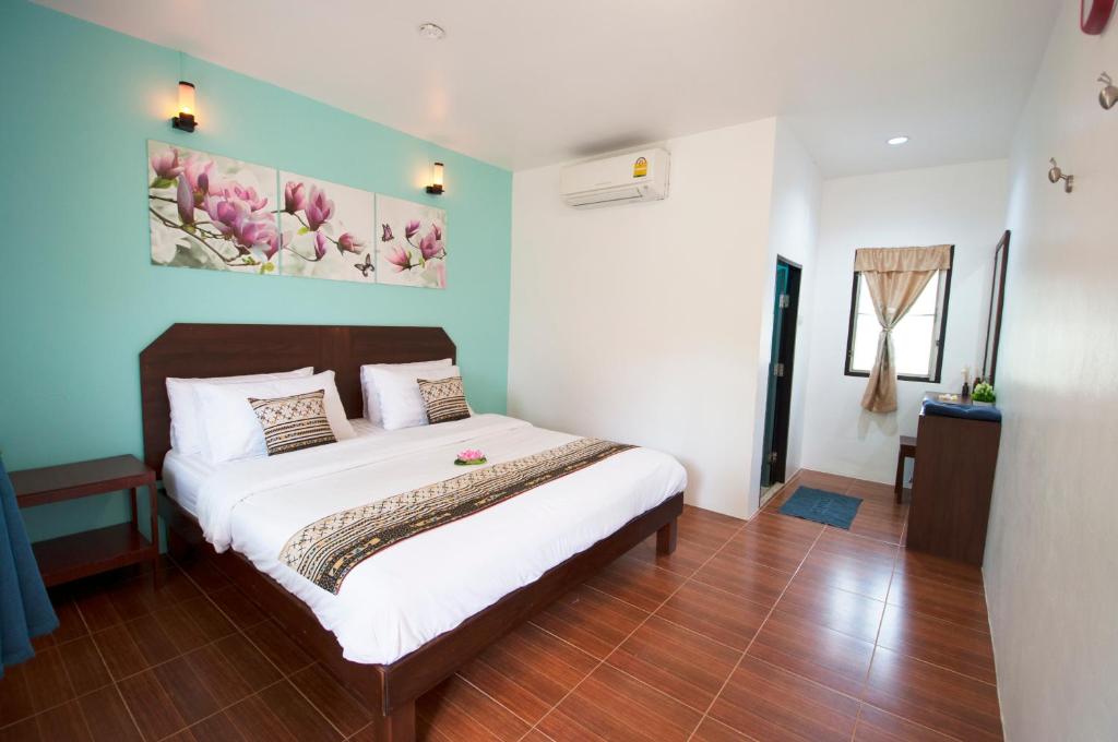 哈林海滩酸酸甜甜之家3号酒店的卧室配有一张床,墙上挂有绘画作品