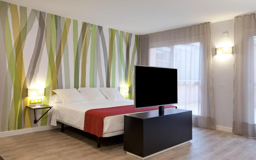 塞维利亚塞维利亚顶点酒店的一间卧室设有一张带平面电视的床。