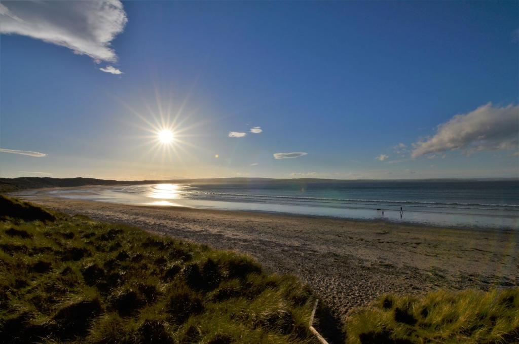 卡斯尔敦Aurora Bed & Breakfast的阳光在海洋上空升起的海滩
