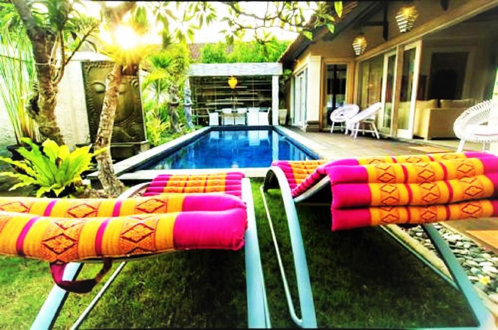 沙努尔竹月别墅的一座房子旁的游泳池,配有两把躺椅