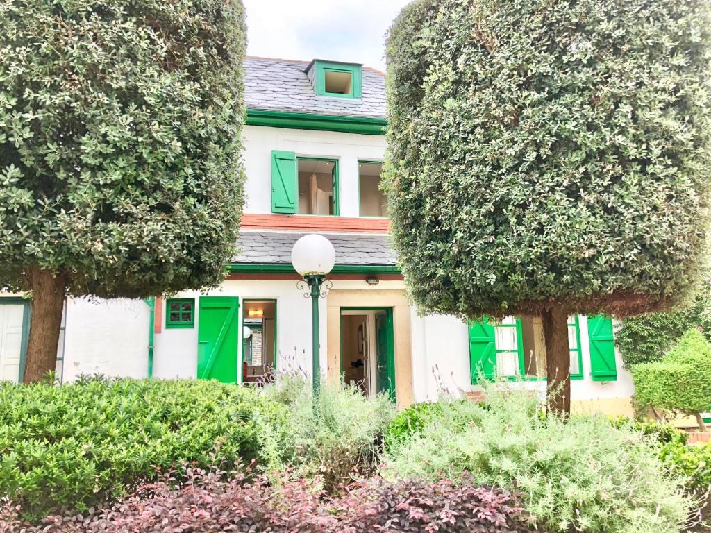 比韦罗Covas Seabreeze Cottage的绿白的房屋,有树木和灌木