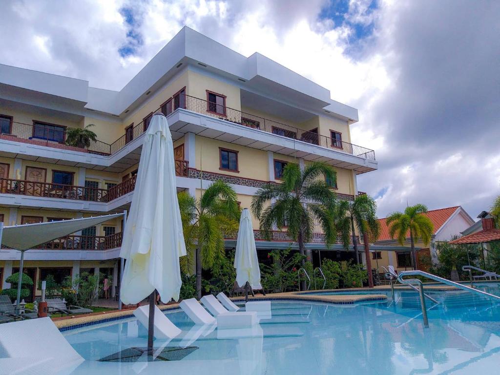 邦劳Sunville Hotel and Restaurant的一座带游泳池和两把白色遮阳伞的酒店