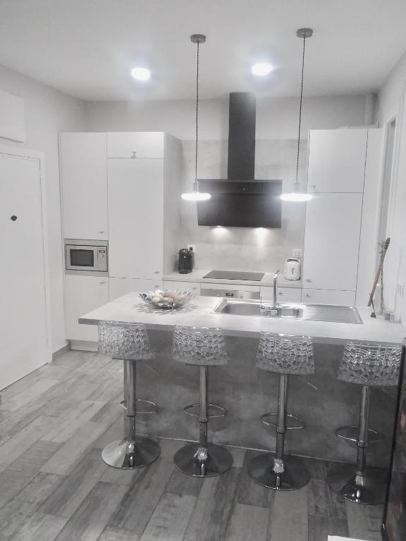 马德里Apartamento estilo nórdico en Malasaña (Madrid Centro)的带水槽和带凳子的柜台的厨房