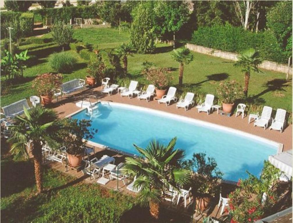 BuxyLes Songes de Buxy的享有带椅子和棕榈树的游泳池的顶部景致