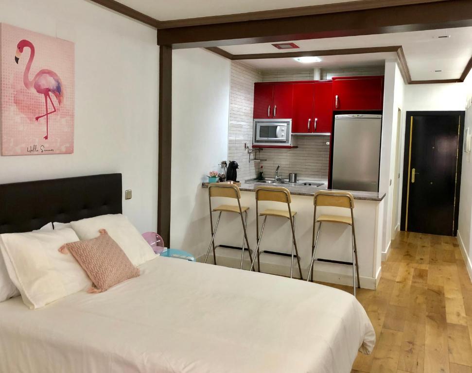 马德里CHUECA Apartamentos的一间卧室配有一张床,厨房配有红色橱柜