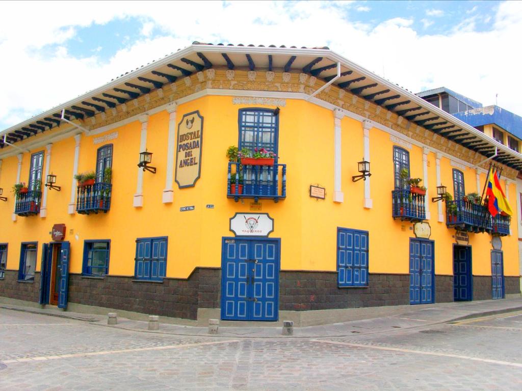 昆卡Hotel Posada del Angel的黄色的建筑,设有窗户和阳台,位于街道上