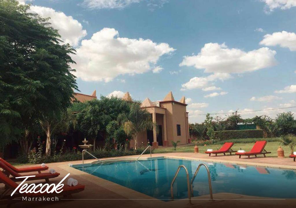 Ouled el guerneTeacook Marrakech的一个带两把椅子的游泳池以及一座房子
