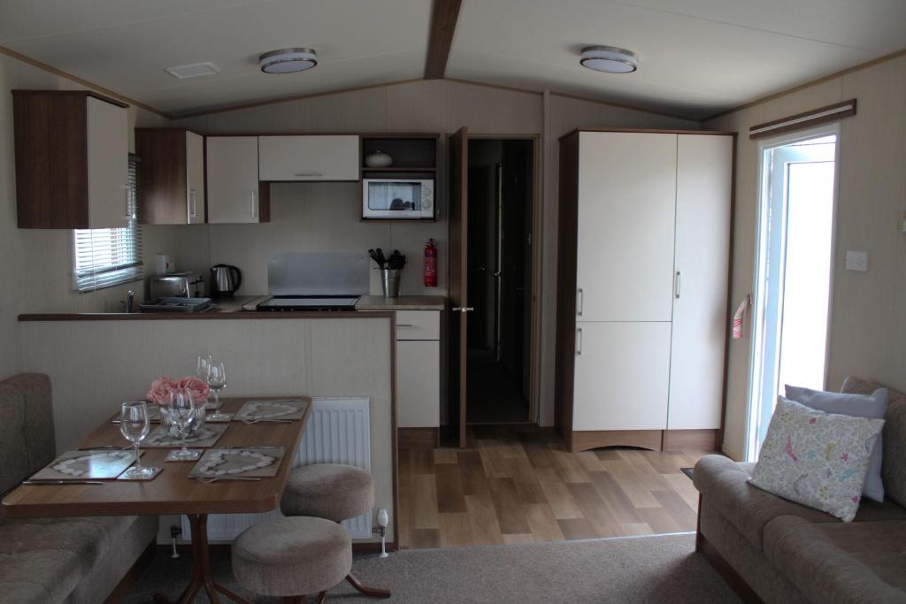 佩恩顿3 Bed Static Caravan @ Hoburne Devon Bay的一间带桌子的客厅和一间厨房