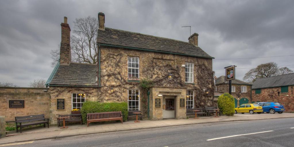 温特沃斯Rockingham Arms By Greene King Inns的街道拐角处的古老石头建筑