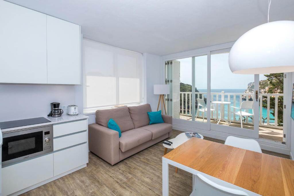 马翁Apartamentos Playa Canutells的客厅配有沙发和桌子